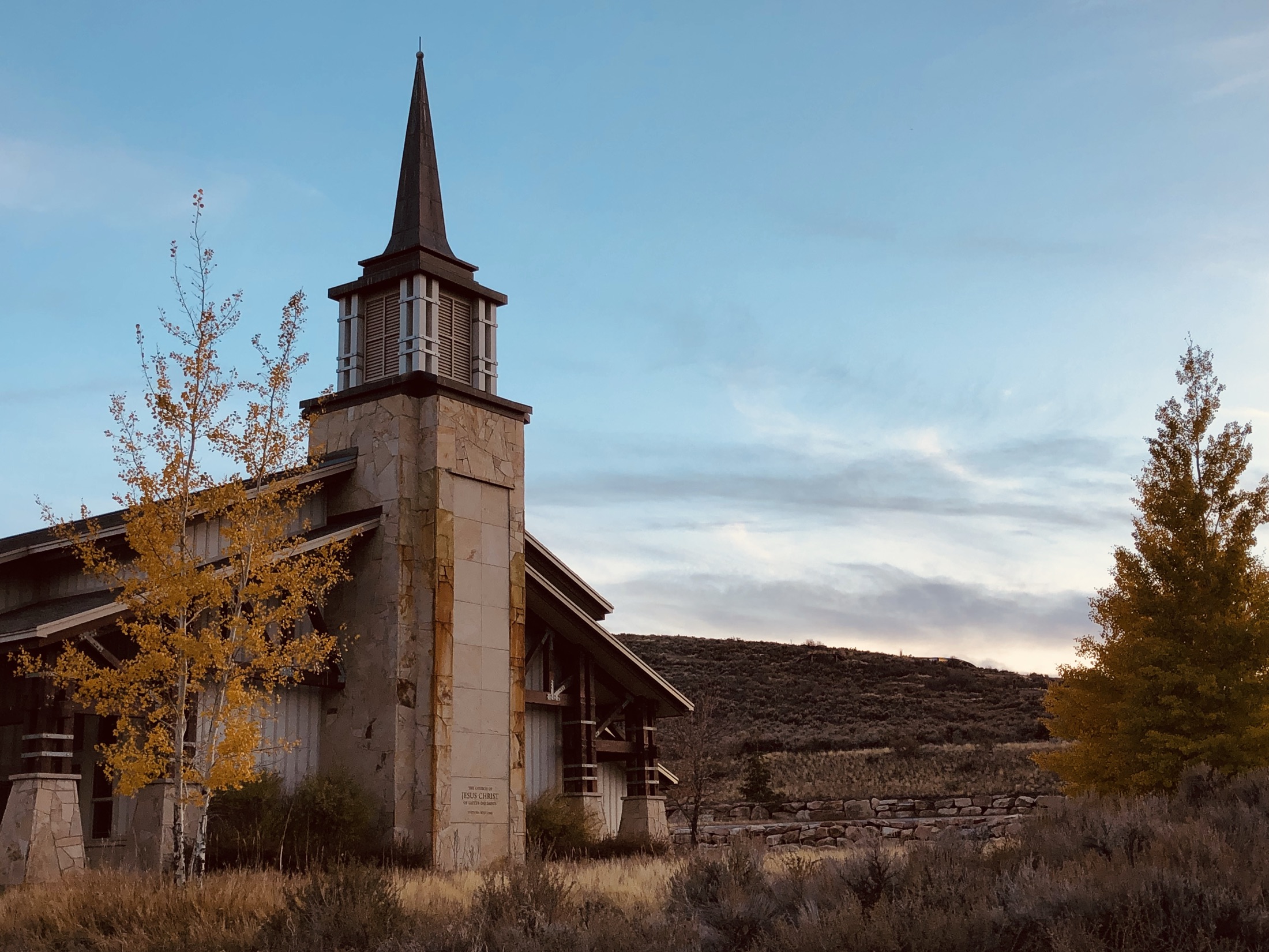 The Snyderville meetinghouse steeple at dusk, framed by golden aspens and the hills above Park City